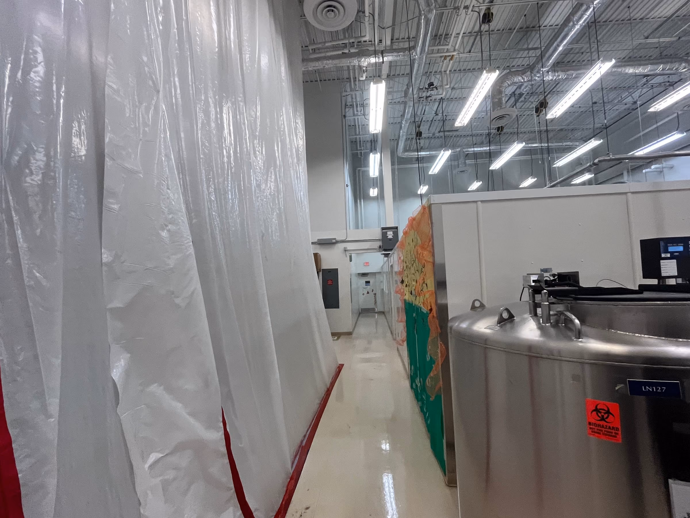 Sealed containment barriers separating an active work area from an occupied laboratory corridor